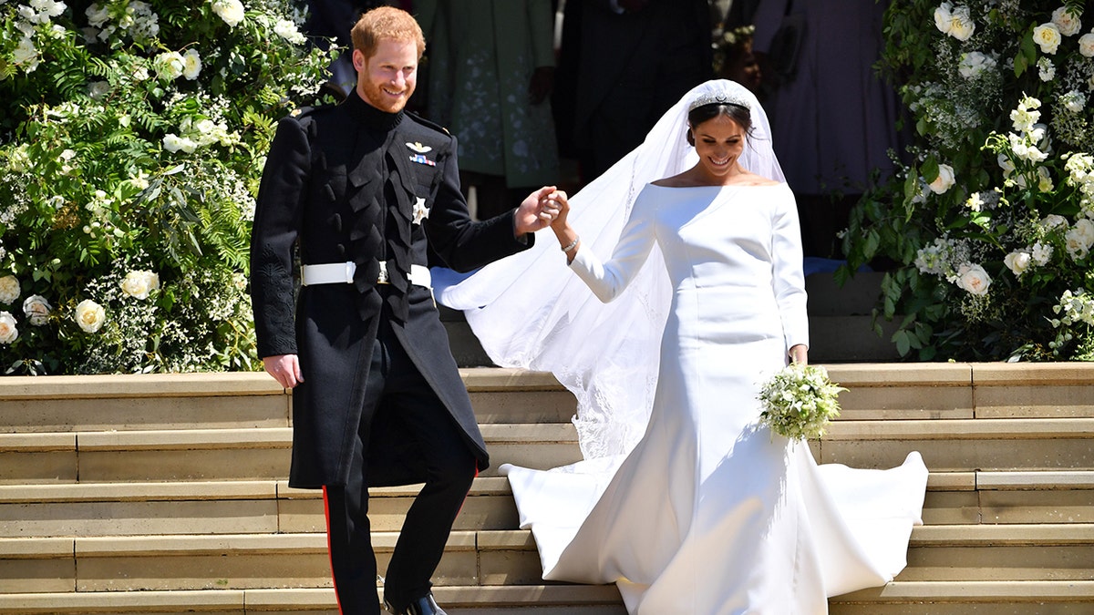 Prince Harry holds Meghan Markle's hand as they walk down the stairs at George's Chapel where they just got married at Windsor Castle