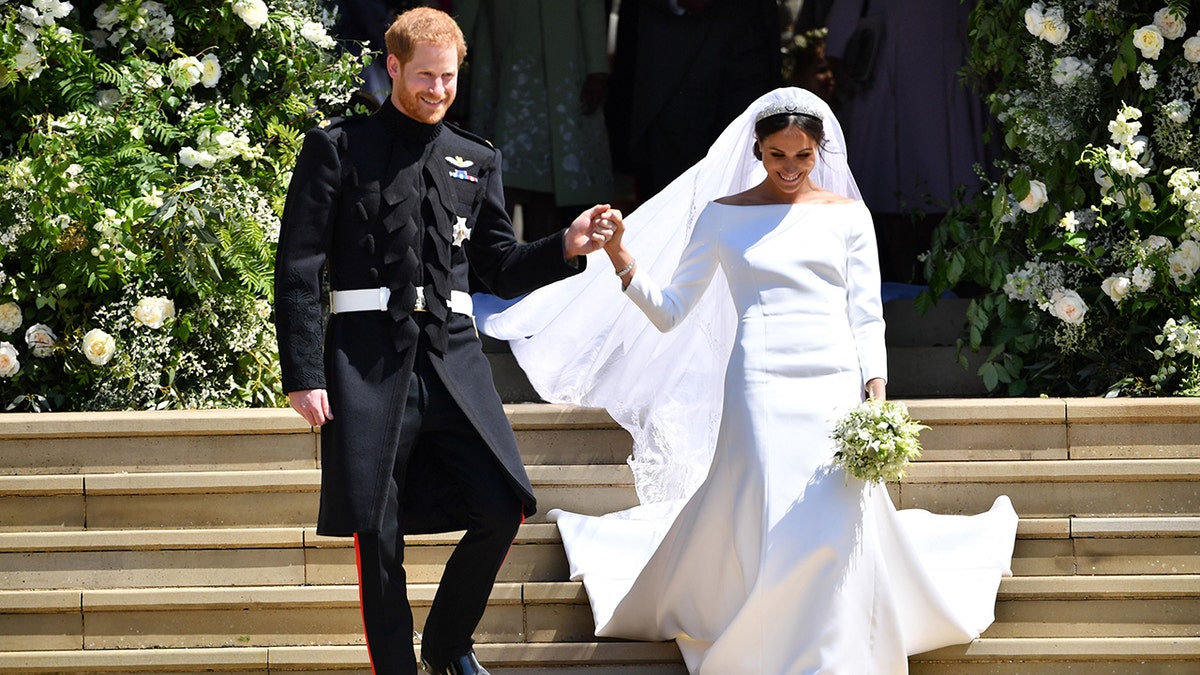 Prince Harry holds Meghan Markles hand as they walk down the stairs at Georges Chapel where they just got married at Windsor Castle