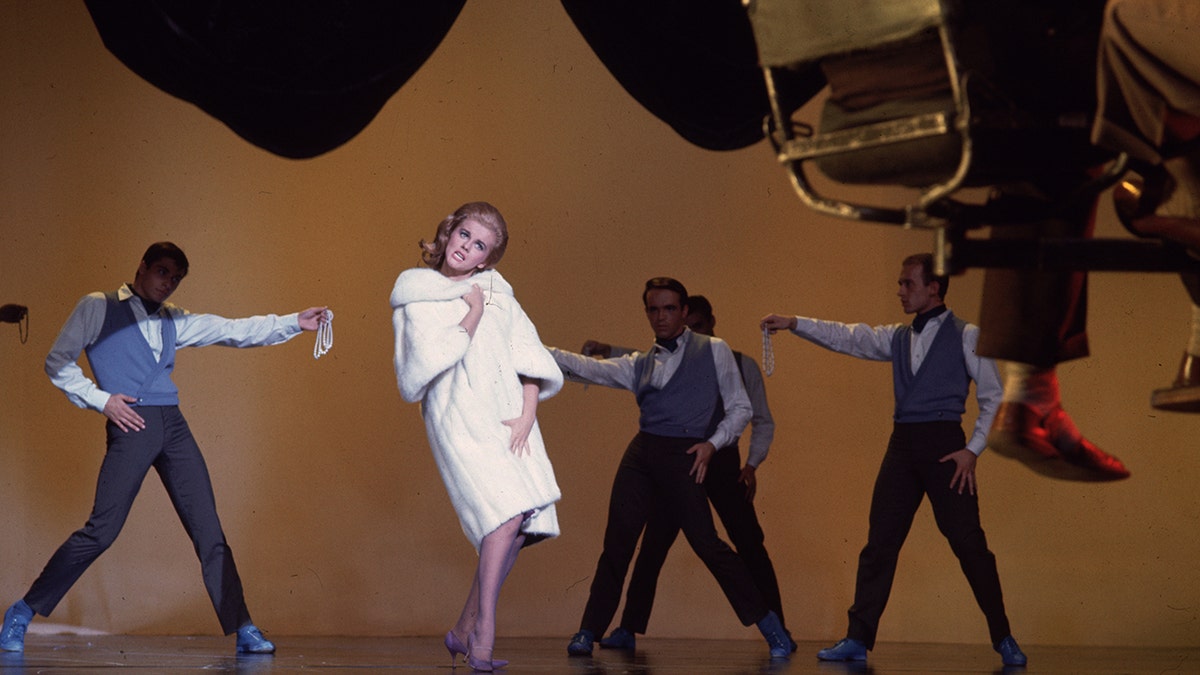 Ann-Margret wearing a white coat while performing on stage