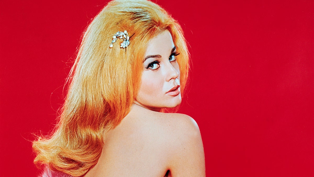Ann-Margret wrapped in pink fur looking towards the camera