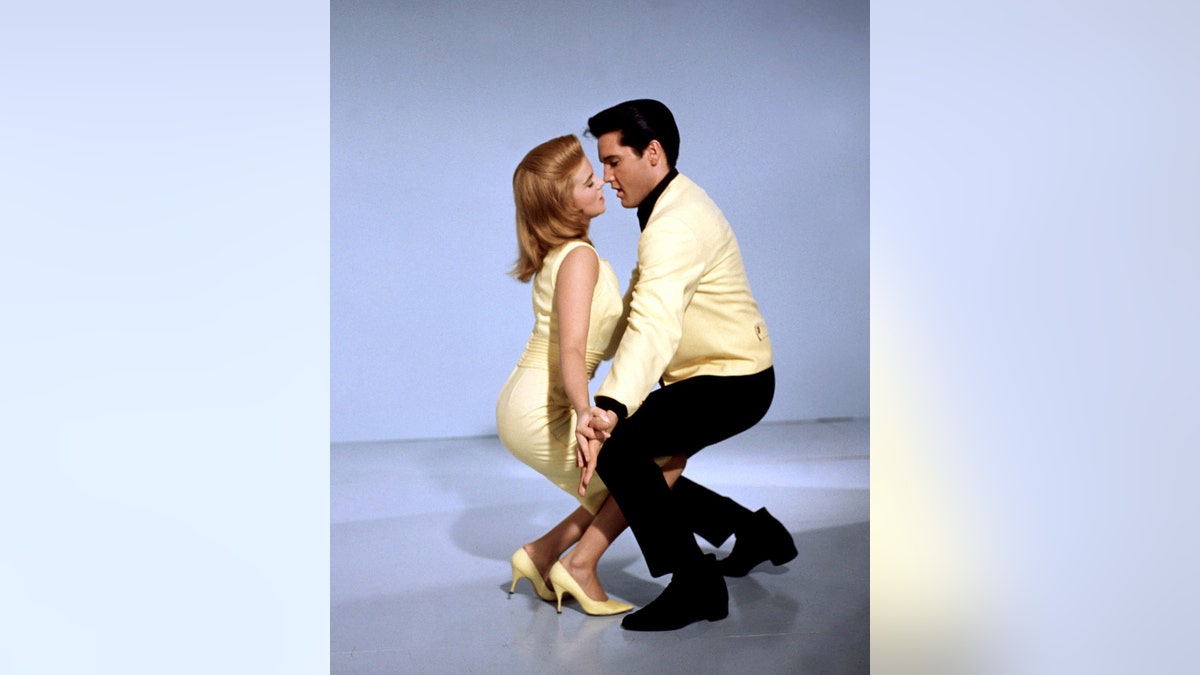 Ann-Margret in a yellow sleeveless dress and Elvis Presley in a yellow shirt and black pants dancing