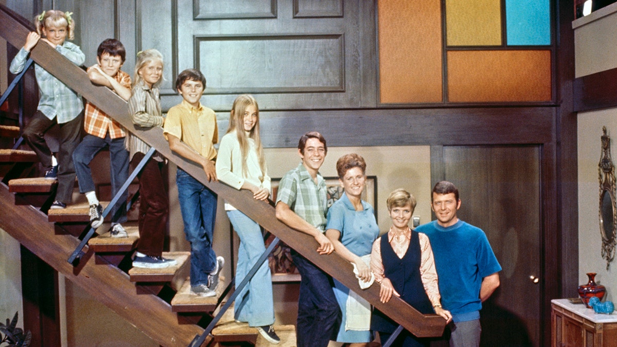 The cast of the Brady Bunch posing on the steps