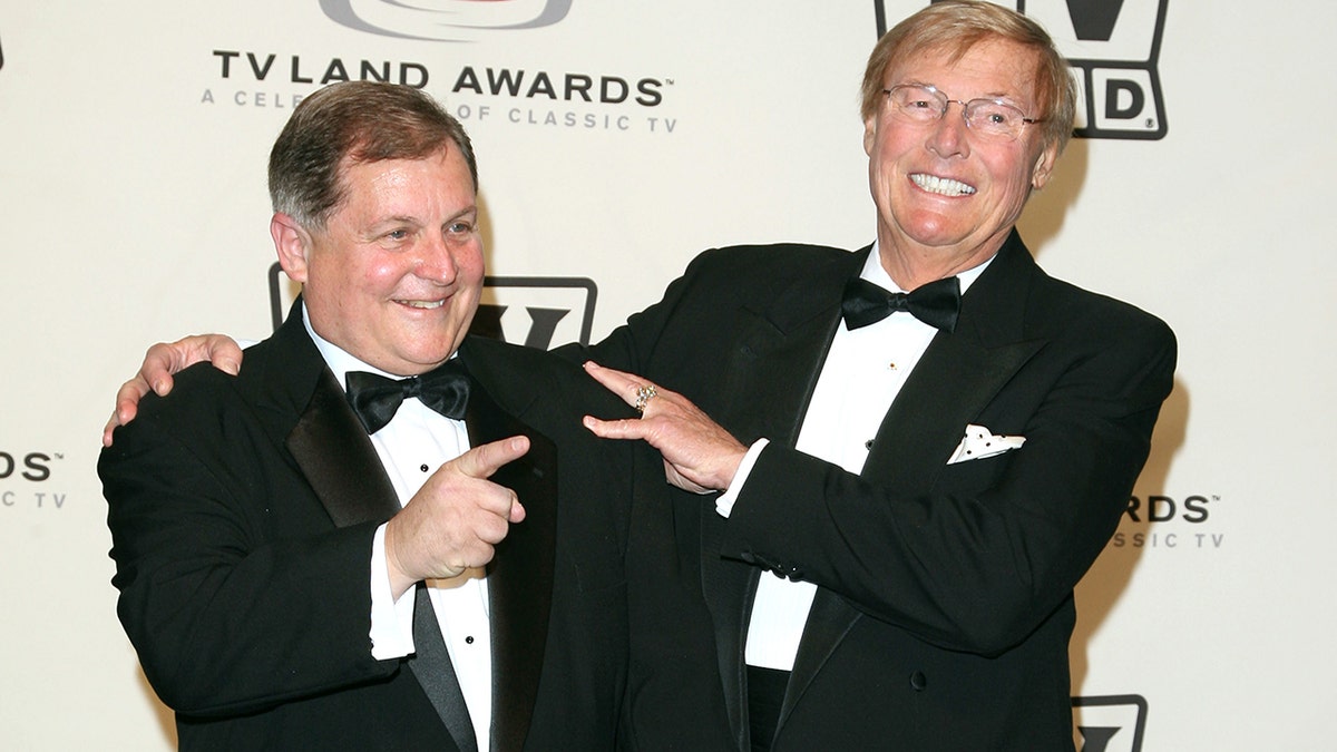 Burt Ward and Adam West in tuxes embracing each other