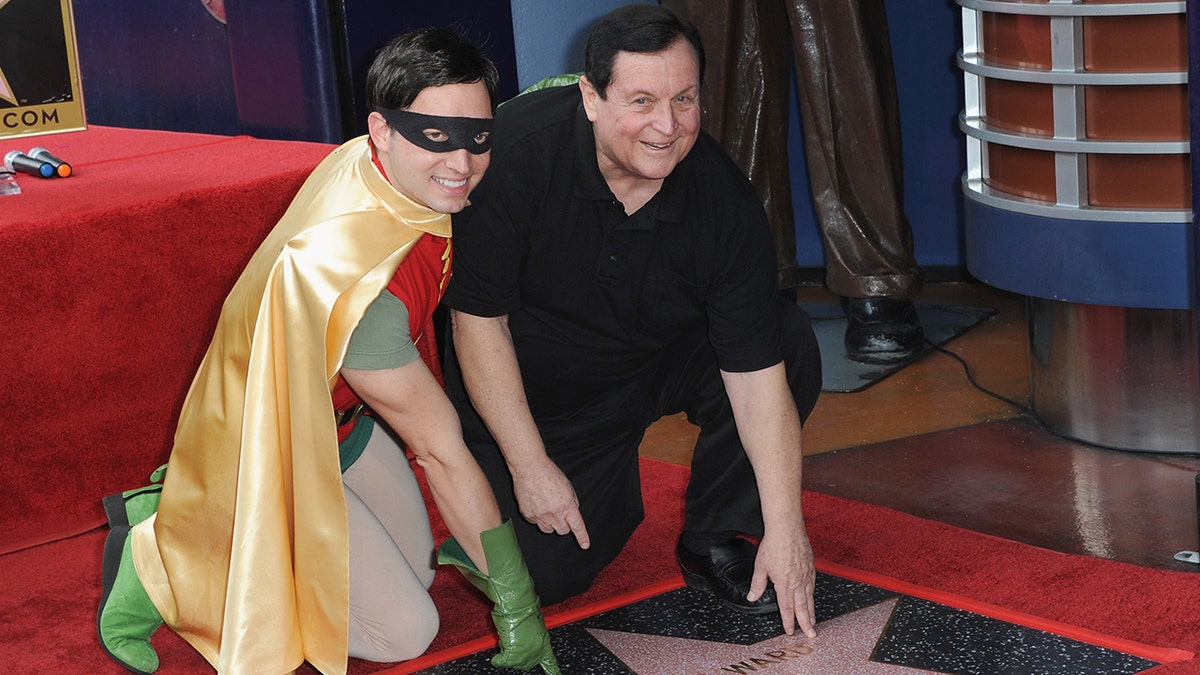 Burt Ward with a Robin impersonator bending down to touch a star on the Hollywood walk of fame
