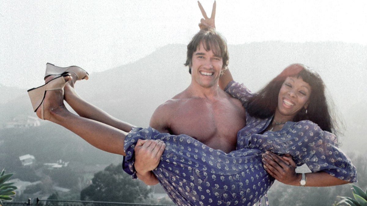 Arnold Schwarzenegger holding up Donna Summer