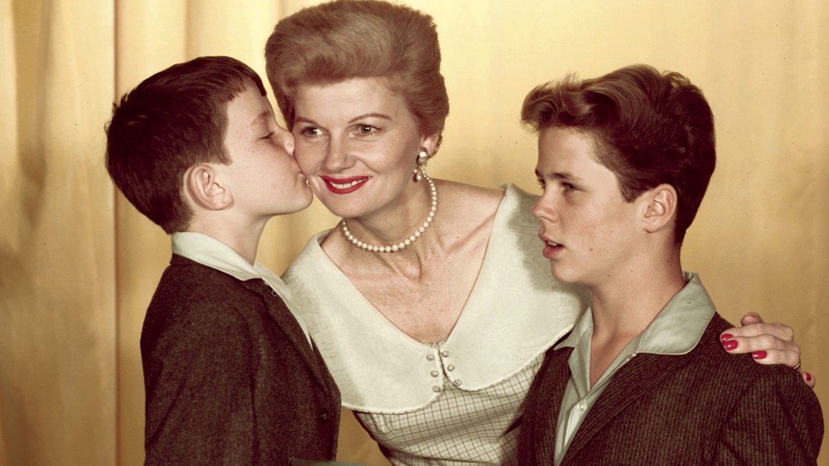 Jerry Mathers giving a kiss on the cheek to his TV mom as fellow child star Tony Dow looks on.