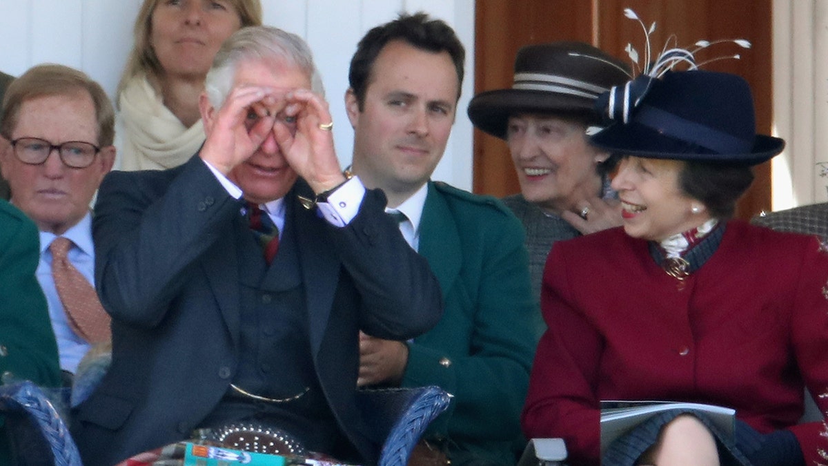 King Charles being silly next to Princess Anne who is wearing a burgundy coat