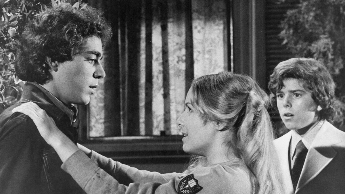 Kym Karath putting her arms around Barry Williams while filming The Brady Bunch