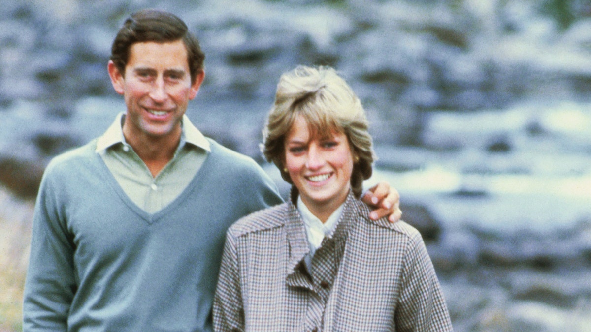 Princess Diana in a green outfit next to Prince Charles in a light blue sweater outside in Scotland