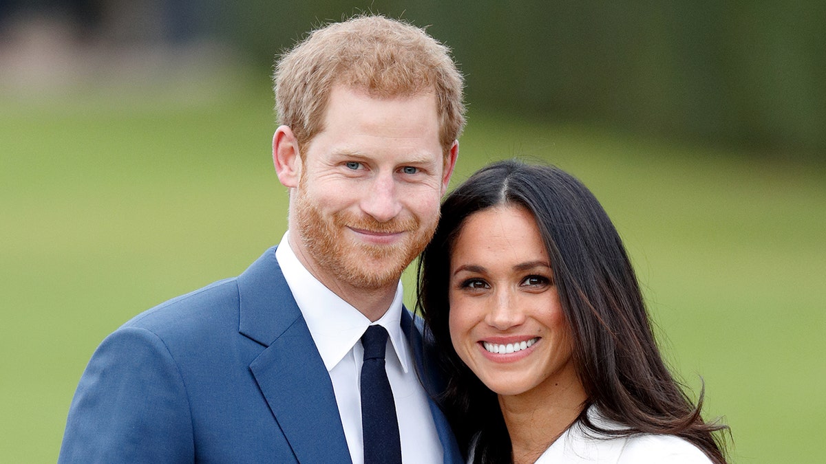 a close-up of Prince Harry in a blue suit and tie with meghan markle wearing a white coat