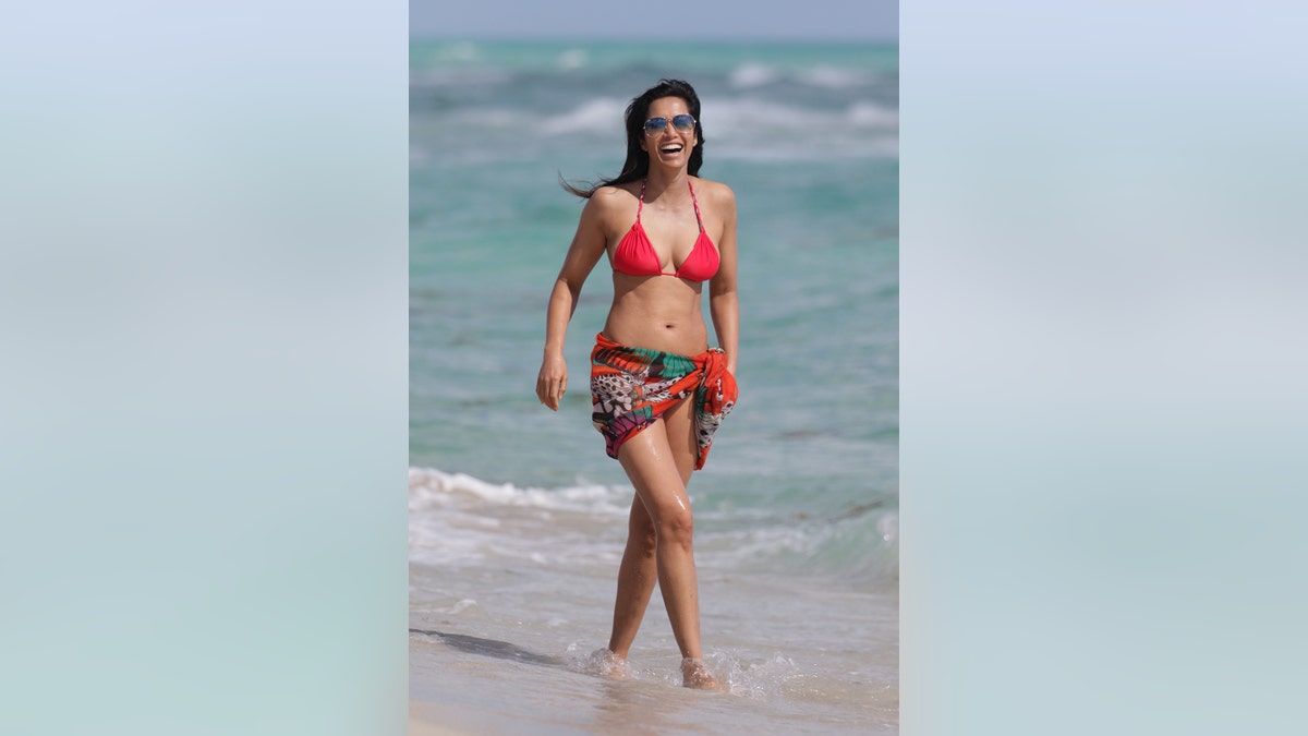 Padma Lakshmi wearing a bright red bikini on the beach