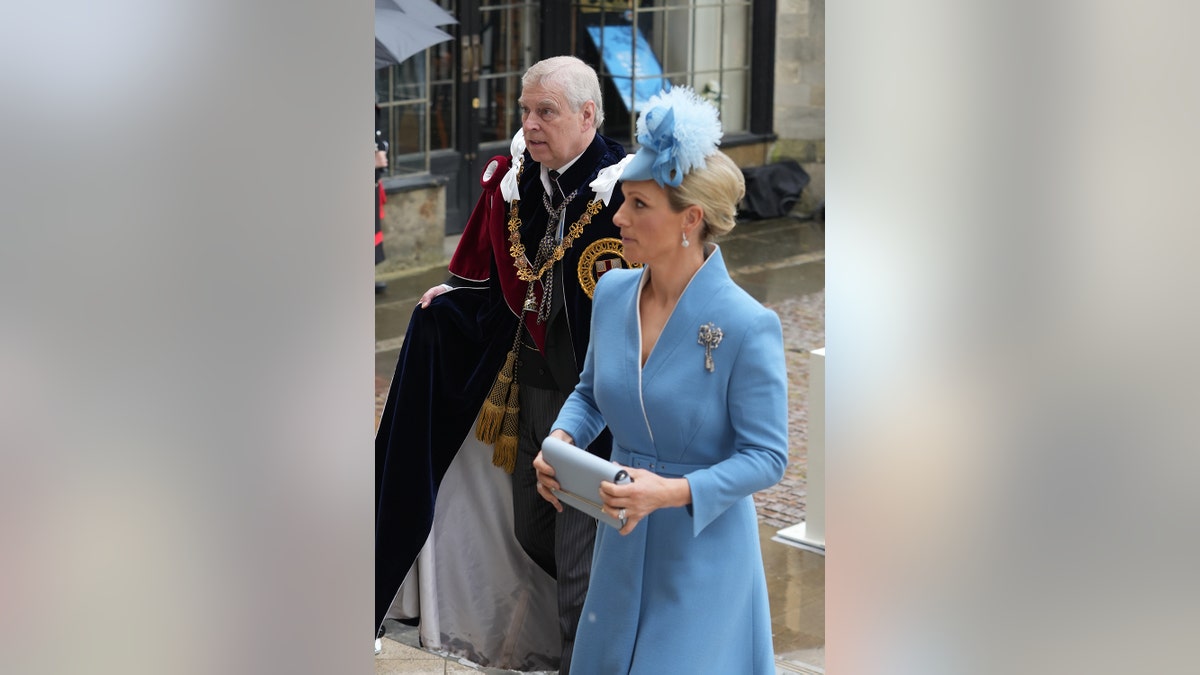 Prince Andrew in royal robes walking alongside Zara Tindall in a light blue dress