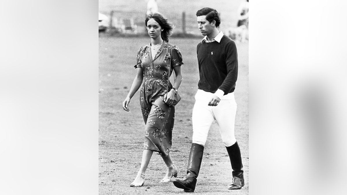 Prince Charles in a polo outfit walking alongside Sabrina Guinness in a printed dress