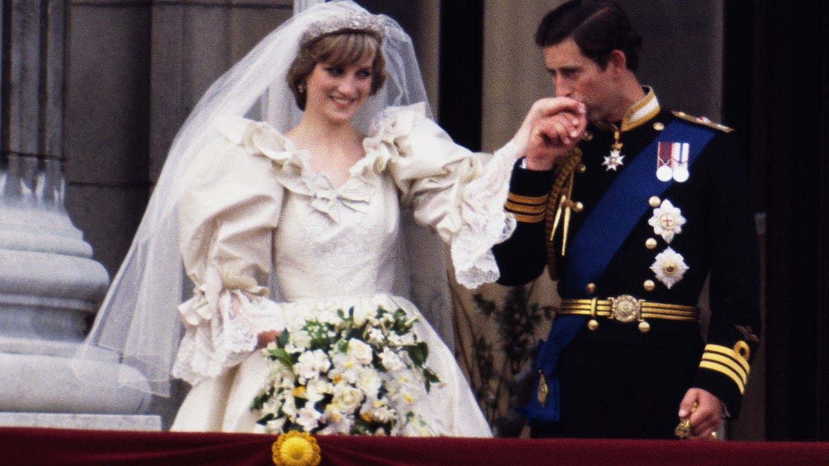 Princess Diana in a bridal gown having her hand kissed by her groom Prince Charles