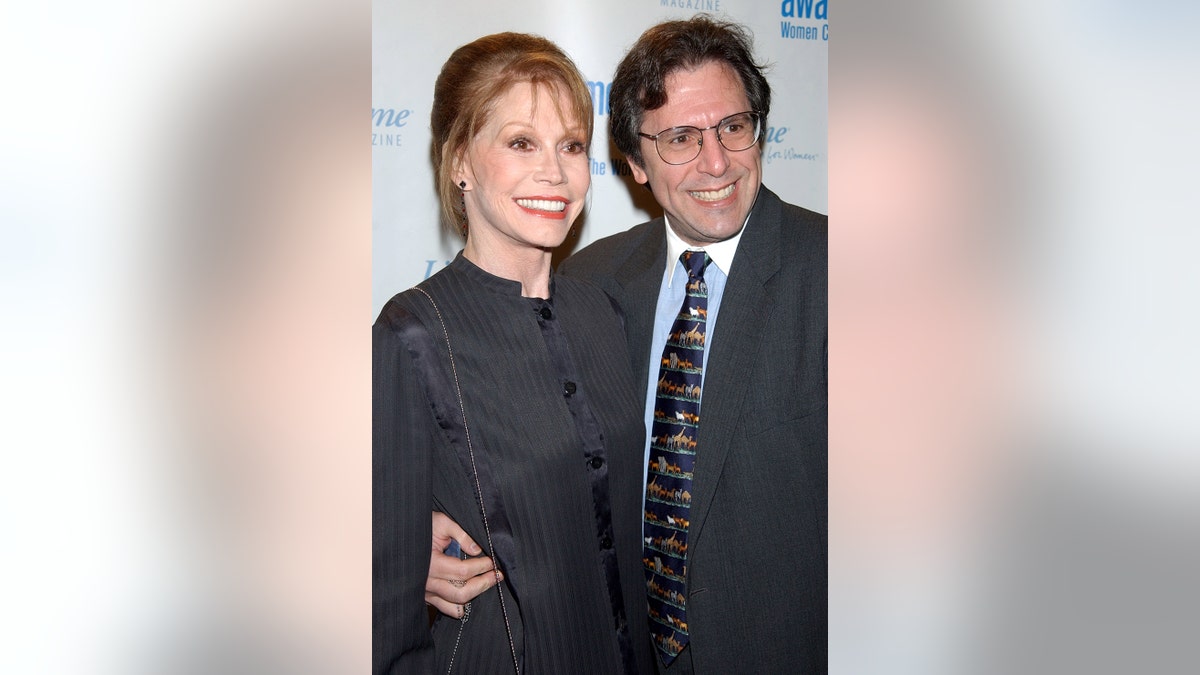 Marty Tyler Moore in a dark suit being embraced by Dr. Robert Levine wearing a matching suit, a blue shirt and a colorful tie