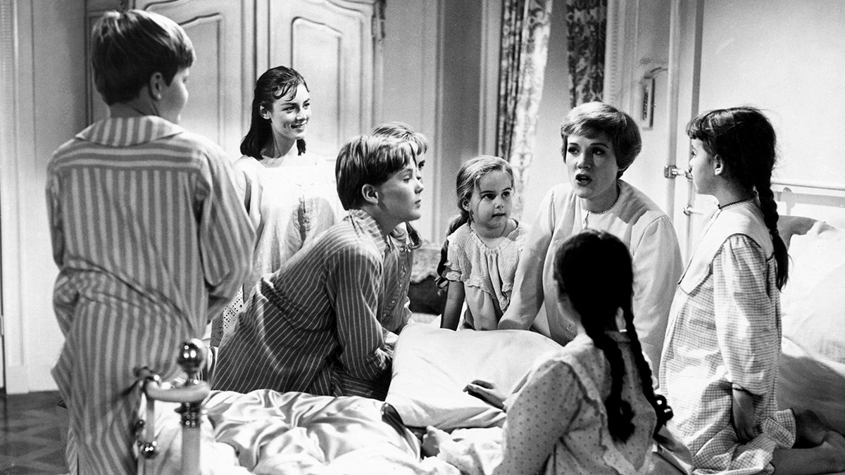 Julie Andrews in bed wearing pajamas telling the von trapp children a story