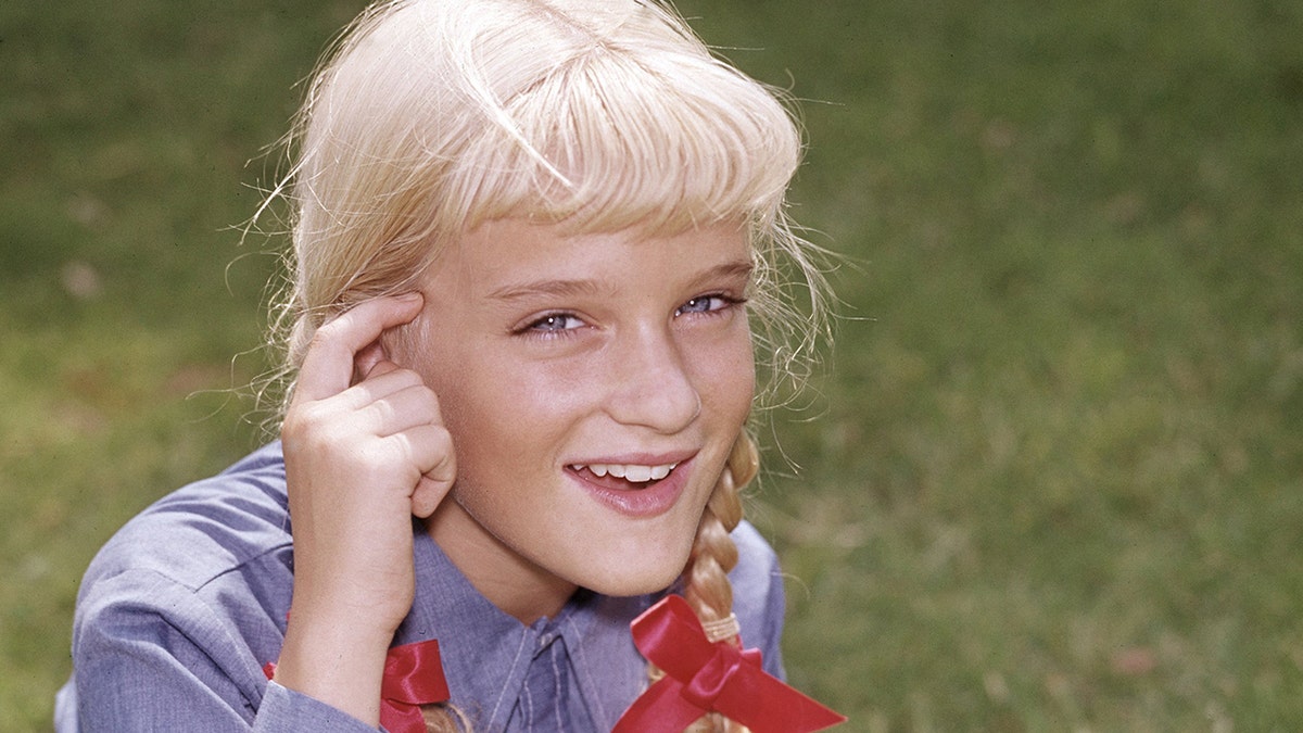 Susan Olsen as Cindy Brady in a blue bloouse and red pigtails
