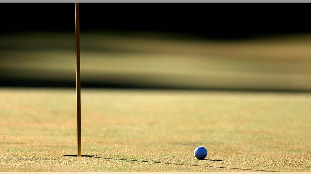 Golf ball next to hole