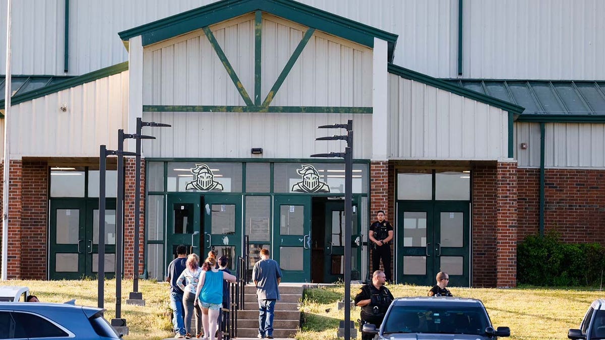 Law enforcement stand outside of Henryetta High School on Monday