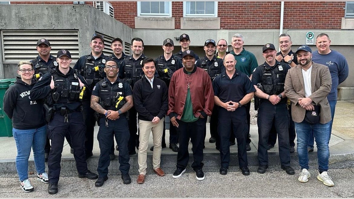 Kenan Thompson with Newport Governor Xay Khamsyvoravong center around police officers of the NPD