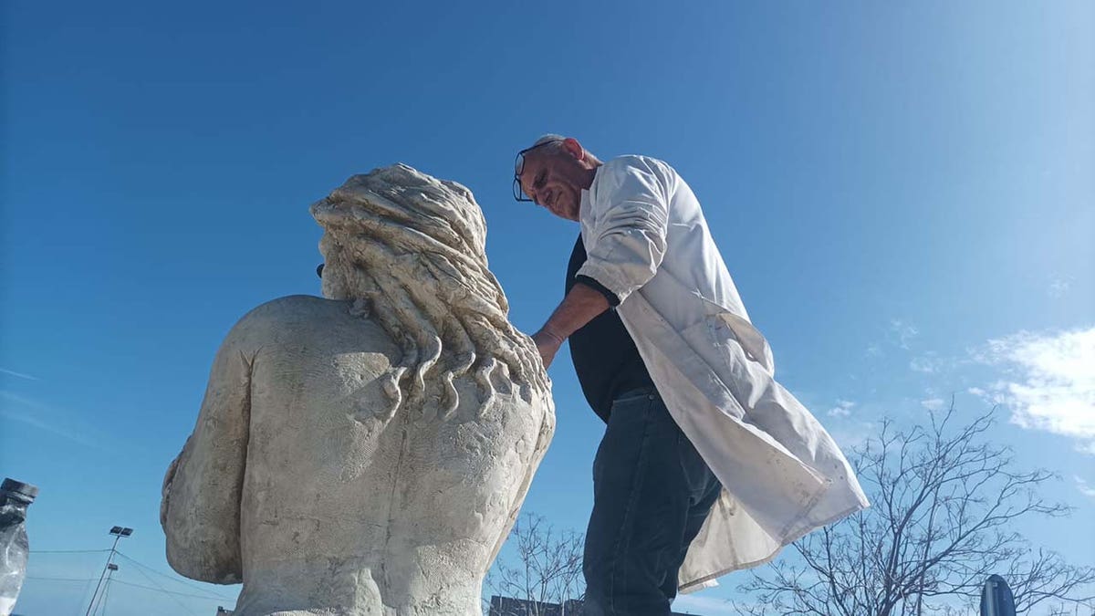 Artist adds finishing touch to mermaid statue