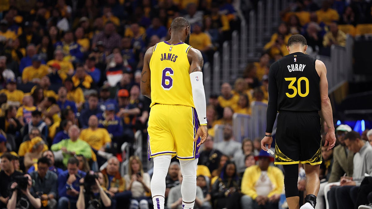 LeBron James stands next to Steph Curry on the basketball court