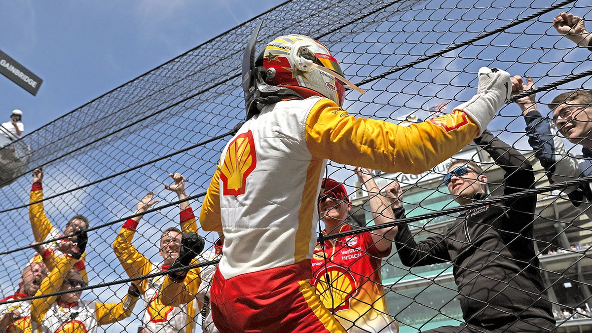 Josef Newgarden climbs the catch fence