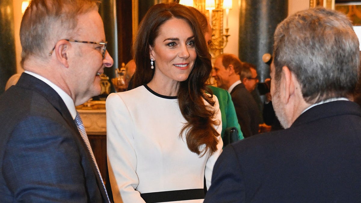 Kate Middleton smiling with two gentlemen at an event
