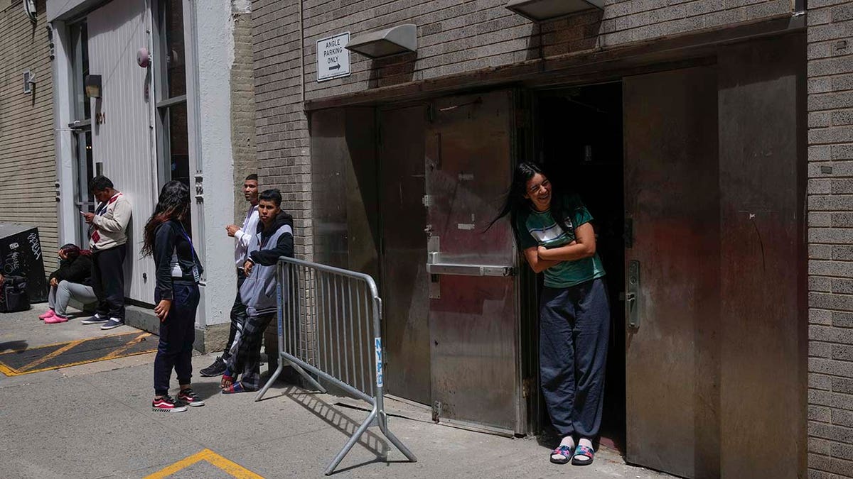 People stand by the door of a former NYPD police academy, where new immigrants to the city are being temporarily housed