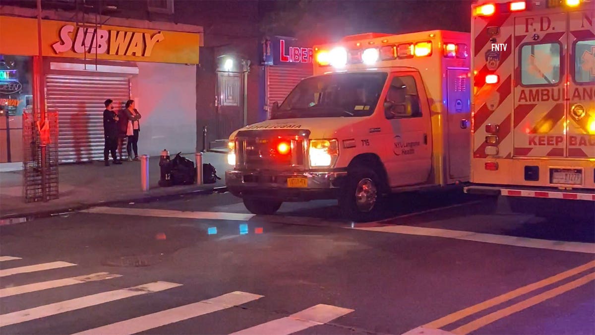 Ambulance driving down the street in front of a Subway.