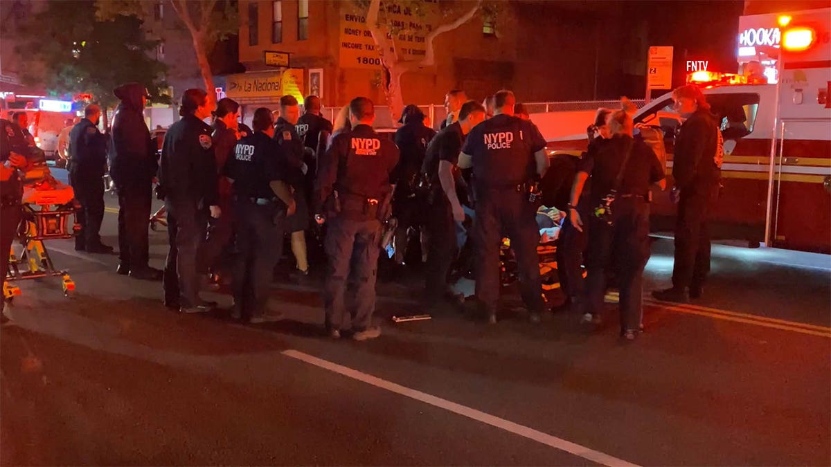 NYPD officers standing on the street next to an ambulance.