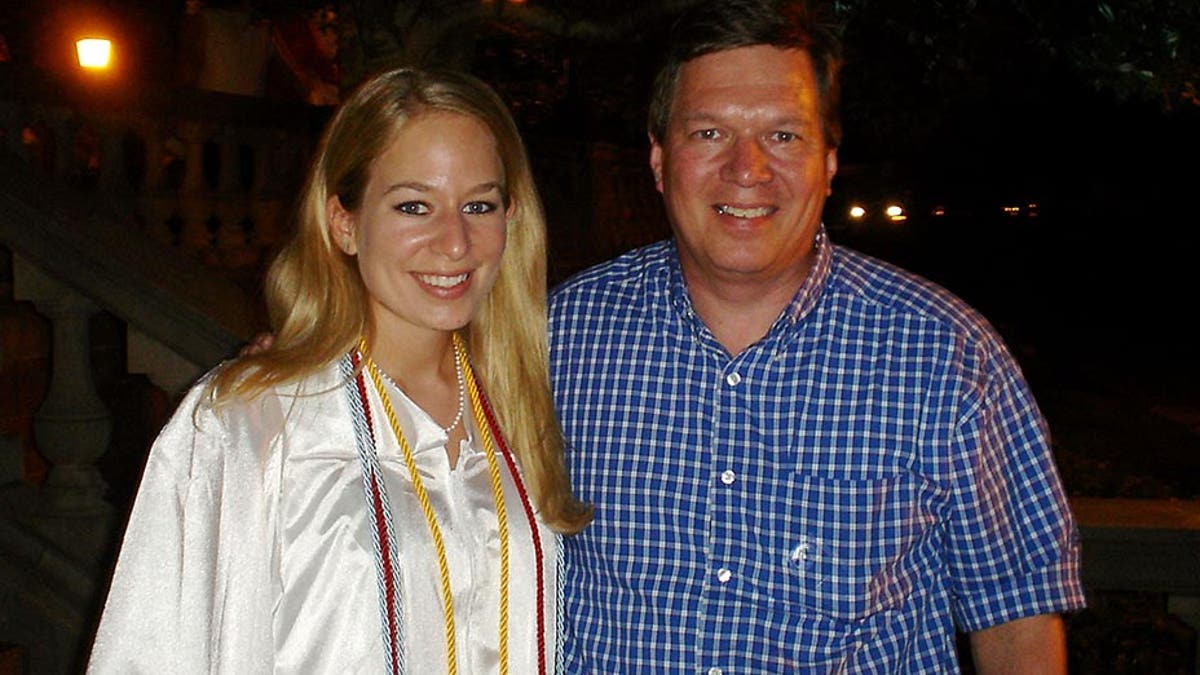 Natalee is in a white cap and gown as she stands with her father, Dave