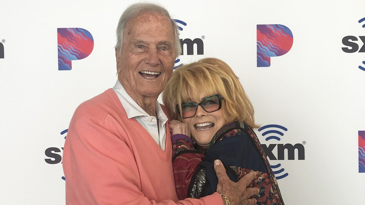 Pat Boone in a pink sweater hugging a smiling Ann-Margret in glasses