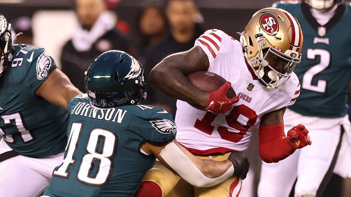 An Eagles player tackles a 49ers player