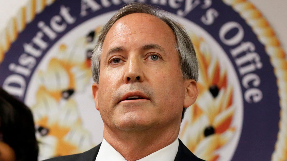 Ken Paxton in front of District Attorney's Office sign