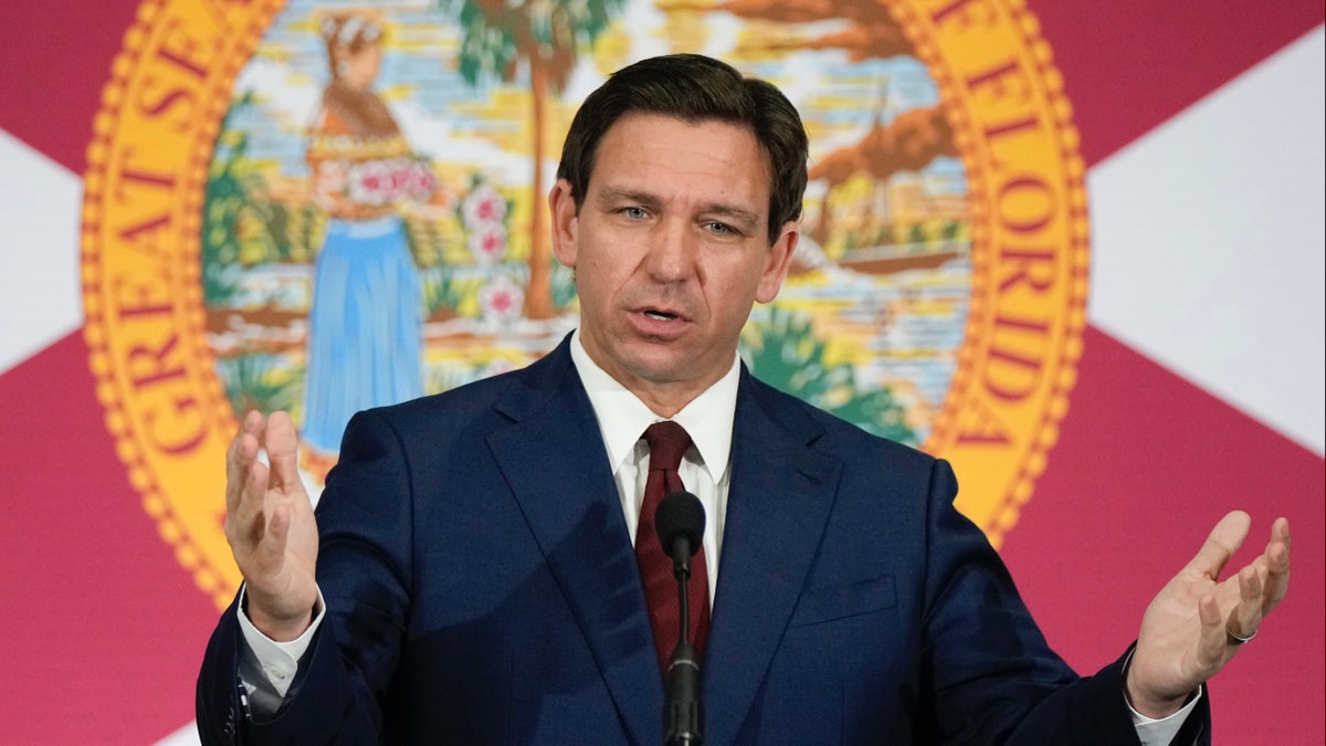 Ron DeSantis speaking in front of a Florida flag