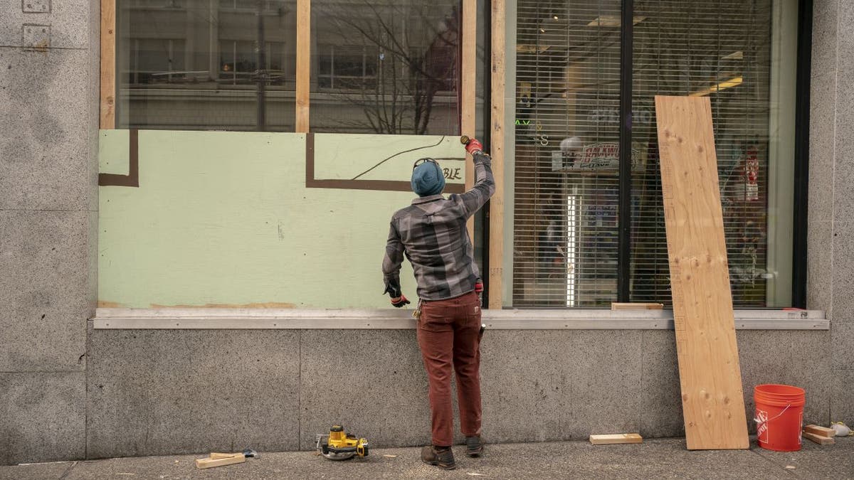man boards up Seattle storefront