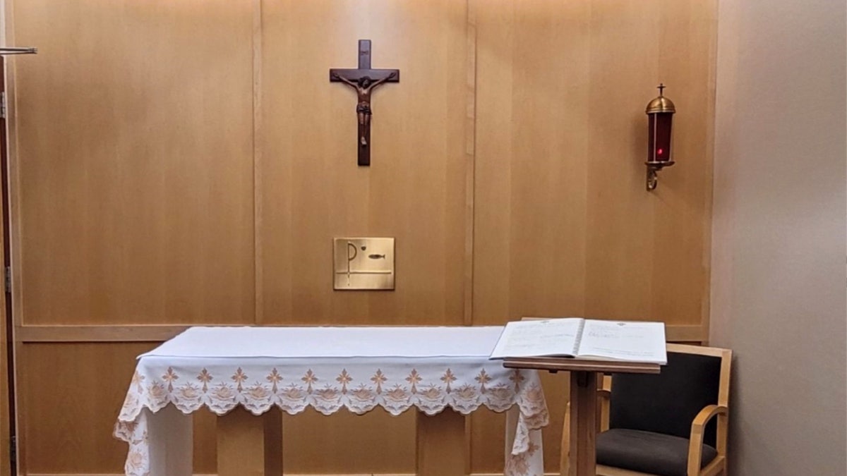 chapel with crucifix center, sanctuary candle at right