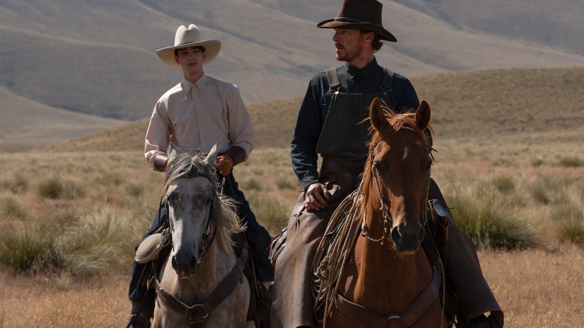 Kodi Smit-McPhee and Benedict Cumberbatch ride horses in a scene from The Power of the Dog