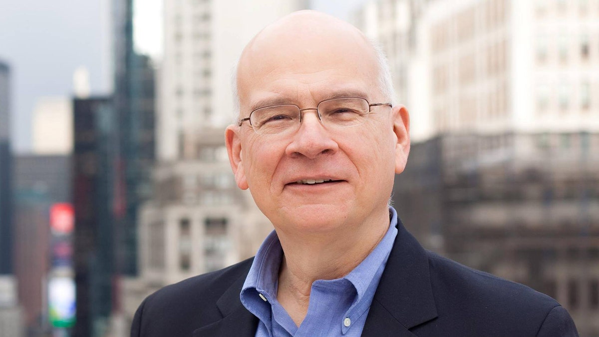 Tim Keller smiling, NYC skyscrapers in background