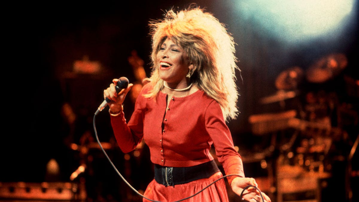 Tina Turner holds a microphone on stage