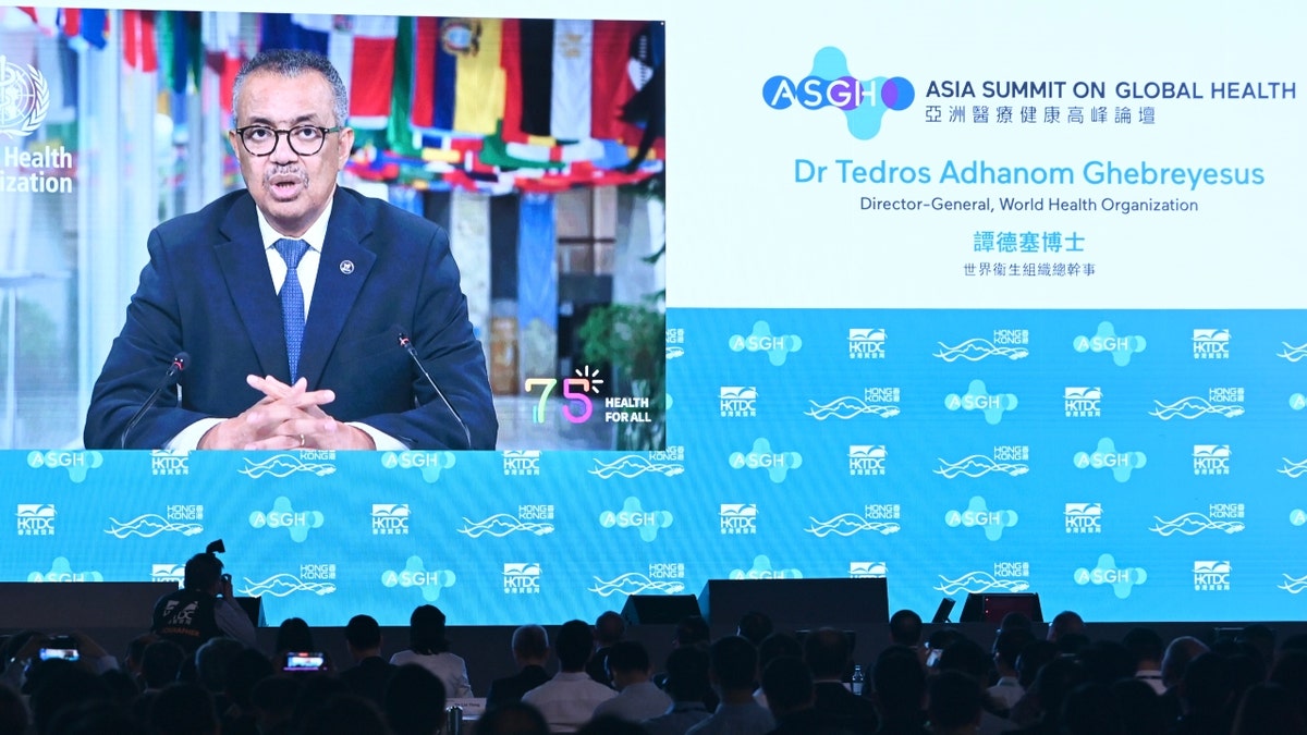 A screen shows World Health Organization (WHO) chief Tedros Adhanom