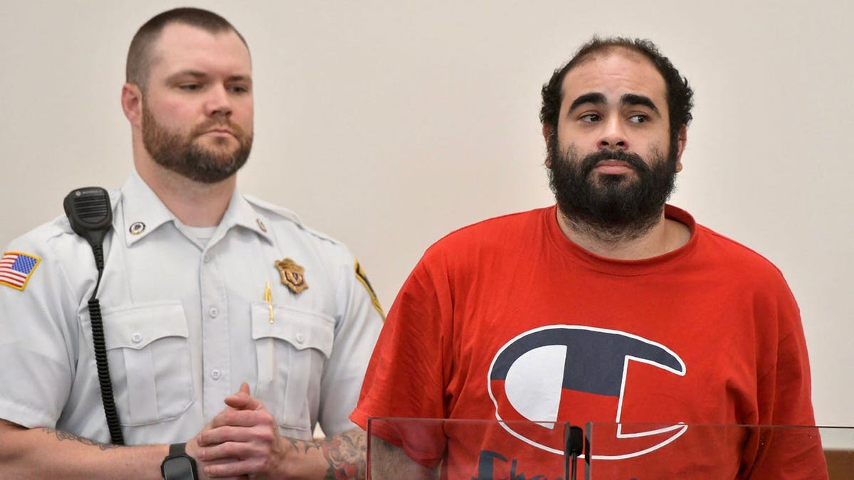 Alberto Sierra Jr. in a red t shirt next to a cop