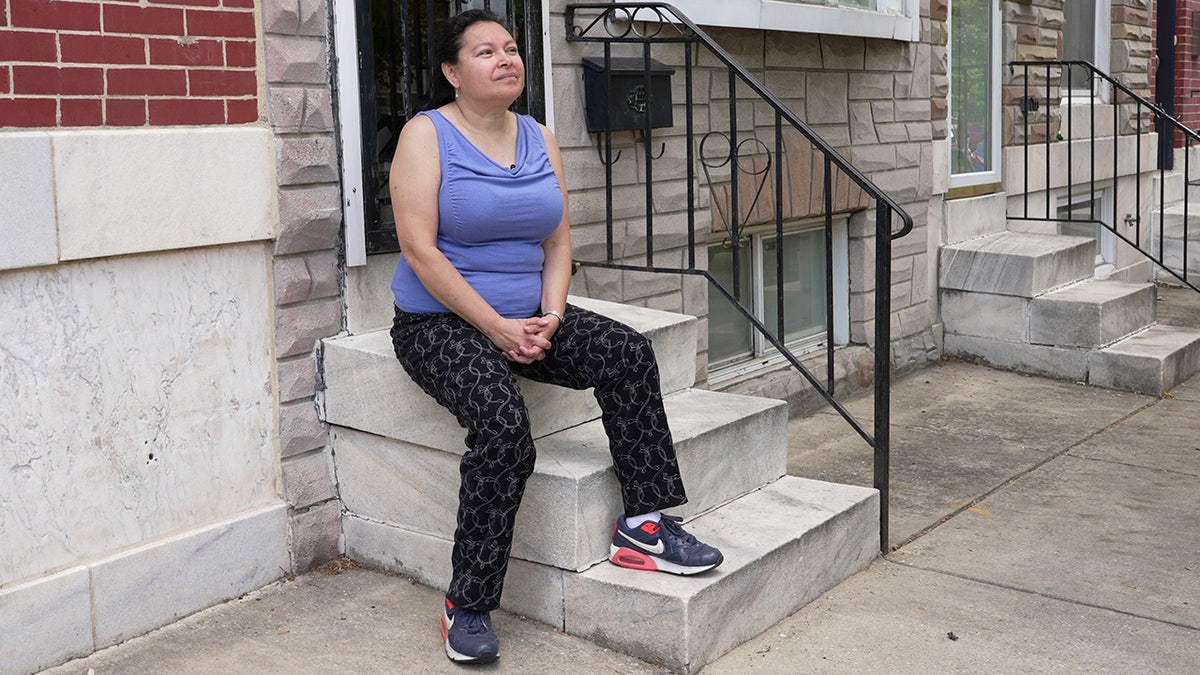 Blanca Tapahuasco sits on the steps outside her Baltimore home