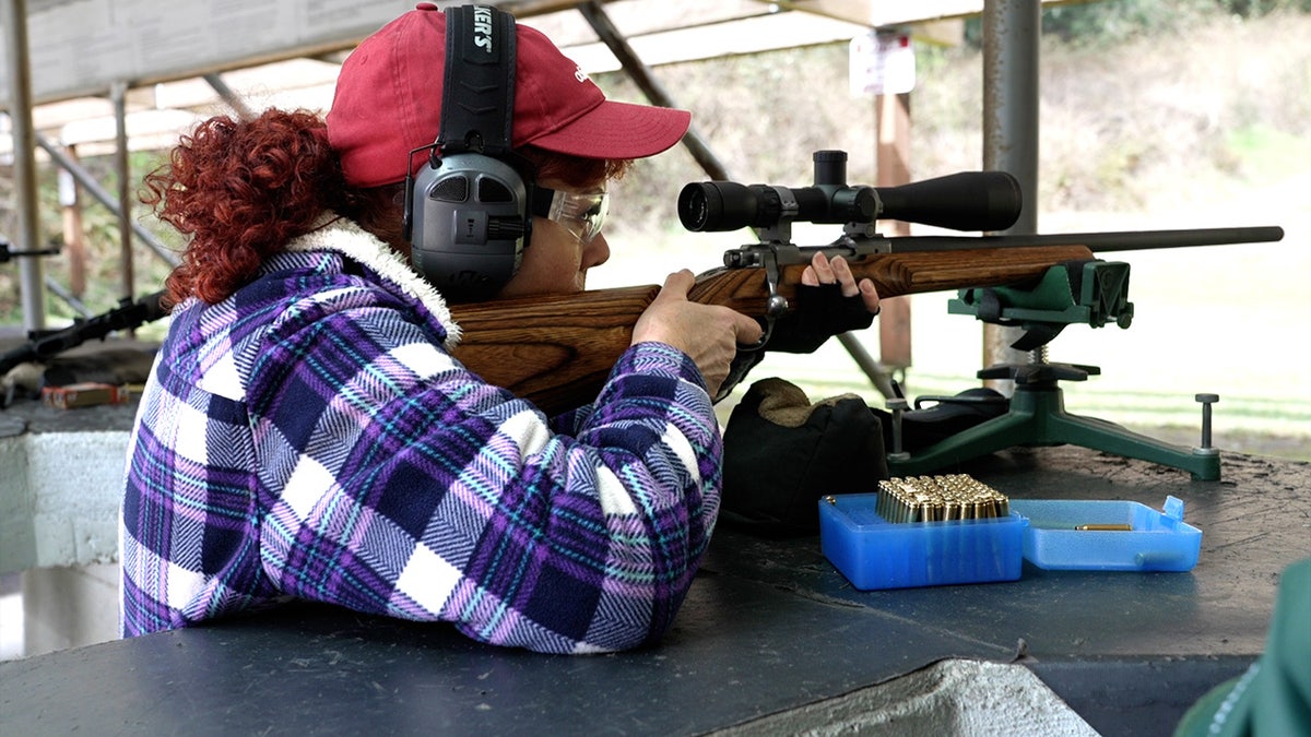 Woman looks through scope on a bolt-action rifle at a gun range near Tacoma, Washington