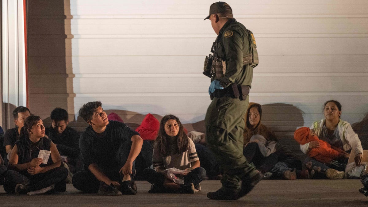 Migrants wait for a bus to take them to a processing center after they turned themselves over to US Border Patrol agents