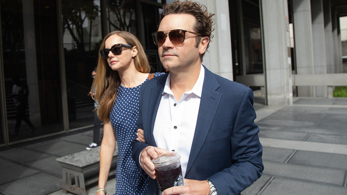 Danny Masterson holds a cup of coffee as he enters the courthouse with his wife Bijou Phillips