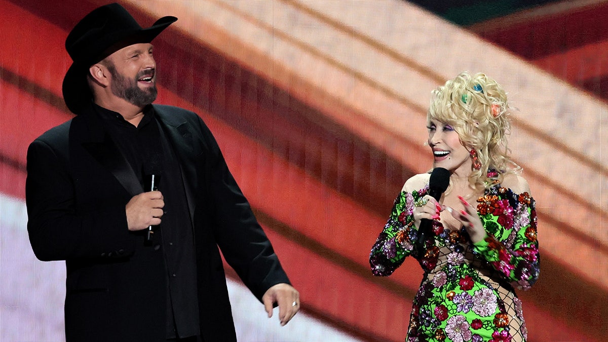 Dolly Parton wears sparkling floral dress on stage with Garth Brooks in black hat and jacket