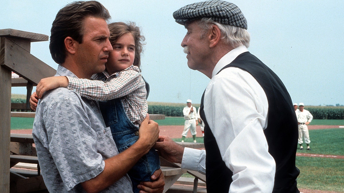Kevin Costner and Gabby Hoffman stand in front of baseball diamond in a Field of Dreams scene
