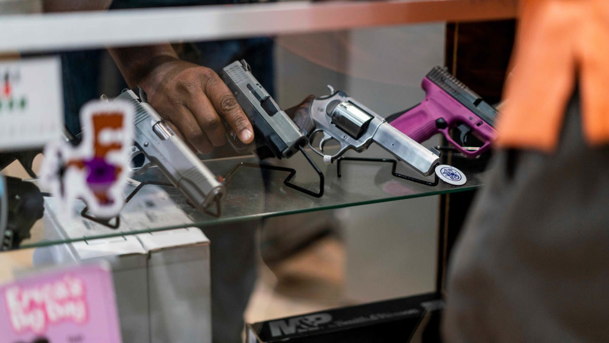 man handles gun in display case